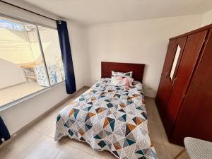 Un dormitorio con una cama con una colcha encima en Ideal para familia de 5, en Ibarra