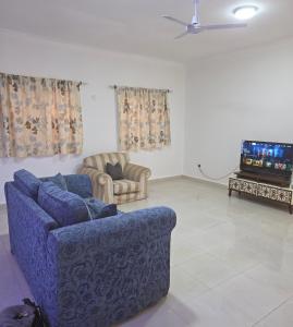 een woonkamer met twee blauwe banken en een tv bij JEK Villa in Brufut