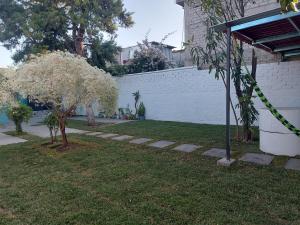 a yard with flowering trees and a white wall at In Oaxaca Casa RodSa in San Agustin de las Juntas