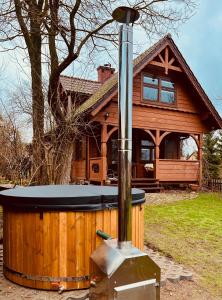 Sosnowy domek w rezerwacie nad Narwią في Bokiny: حوض استحمام ساخن أمام منزل خشبي