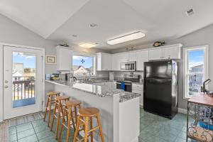 Ocean Views & Coastal Charm at ForeShore OKI في أوك آيلاند: مطبخ بخزائن بيضاء وثلاجة سوداء