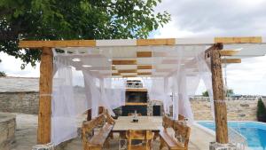 een houten pergola met een tafel en een open haard bij Juniper Stone Cottage by Villas Guide in Alavanja +3 foto's