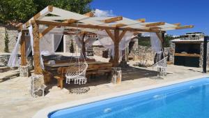 een paviljoen met een tafel en stoelen naast een zwembad bij Juniper Stone Cottage by Villas Guide in Alavanja