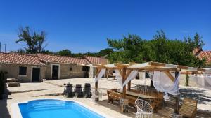 een patio met een zwembad en een huis bij Juniper Stone Cottage by Villas Guide in Alavanja