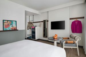 a bedroom with a bed and a table and a tv at Moxy Kathmandu in Kathmandu