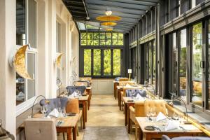 a restaurant with wooden tables and chairs and windows at Bollants SPA im Park, Autograph Collection in Bad Sobernheim