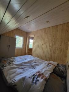 Domek nad jeziorem Wilczyńskim في Świętne: سرير كبير في غرفة بجدران خشبية
