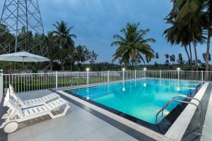 Encanto Farmstay Resort في ميسور: حمام سباحة مع كرسيين ومظلة