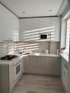 a kitchen with white cabinets and a sink and a stove at 3-bedroom City Center Apartment in Mažeikiai +9 photos