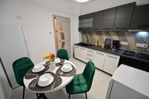 a kitchen with a table and green chairs at FLH - Moonwalk in Sibiu