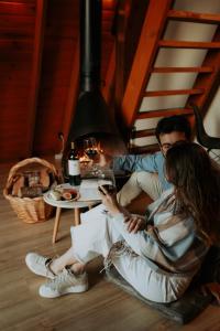 Cabana Amélia, em Gramado في غرامادو: رجل وامرأة يجلسان على الأرض ينظران إلى هاتفهما المحمول