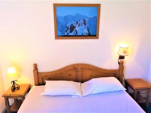 een slaapkamer met een bed met 2 lampen en een foto aan de muur bij Chalet Mitoyen 3 Pièces 7 Pers. avec Piscine et Sauna - Résidence Les Flocons du Soleil - FR-1-863-13 in Le Dévoluy +14 foto's