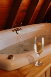 Cabana Amélia, em Gramado في غرامادو: حوض استحمام مليء بالماء وكأس من النبيذ