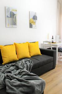 - un canapé noir avec des oreillers jaunes dans le salon dans l'établissement Golden Nest Padova, à Padoue