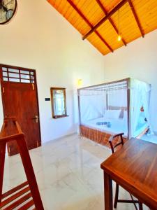 a living room with a wooden table and a bed at Mangrove Inn Mirissa in Kamburugamuwa