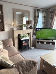 a living room with a couch and a tv and a fireplace at Home from Home at the Hendersons Caravan in Kilwinning