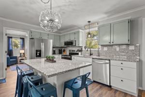 een keuken met witte kasten en een eiland met blauwe stoelen bij 4bdrm OKI Gem - Steps to Beach with Poolside Oasis in Yaupon Beach