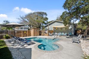 een zwembad met stoelen en een parasol in de tuin bij 4bdrm OKI Gem - Steps to Beach with Poolside Oasis in Yaupon Beach