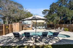 een terras met een tafel, stoelen en een parasol bij 4bdrm OKI Gem - Steps to Beach with Poolside Oasis in Yaupon Beach