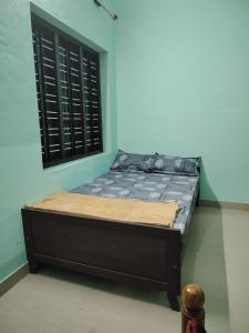 a small bed in a room with a window at JANATHA home stay in Varkala