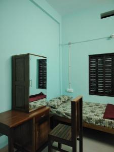 a bedroom with two beds and a dresser and a mirror at JANATHA home stay in Varkala