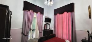 een kamer met roze gordijnen, een bed en een raam bij Art house Venusio luxury home in Napels