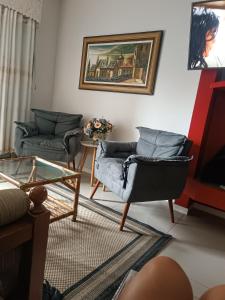 een woonkamer met 2 stoelen en een schilderij aan de muur bij Apartamento Capão Novo in Capão da Canoa