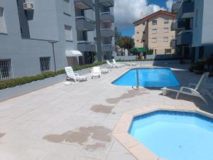 een zwembad met ligstoelen en een zwembad bij Apartamento Capão Novo in Capão da Canoa