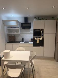 a kitchen with a white table and chairs and a kitchen with a stove at Les 3 anges in Houilles