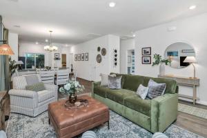 a living room with a green couch and a kitchen at The Augusta Cottage WECO 3Br in West Columbia