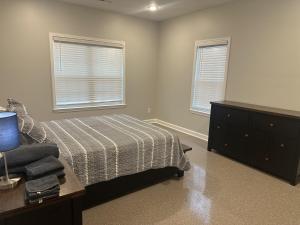a bedroom with a bed and a dresser and two windows at The Buford T Justice Suite in Lexington