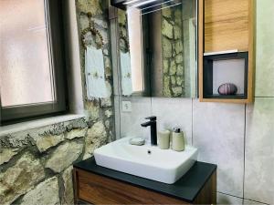een badkamer met een witte wastafel en een stenen muur bij Kösedere Stone Houses in Karaburun +39 foto's