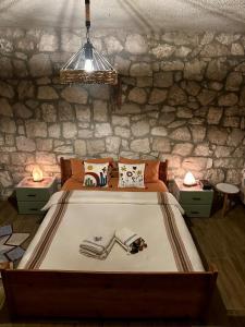 een slaapkamer met een groot bed en een stenen muur bij Kösedere Stone Houses in Karaburun