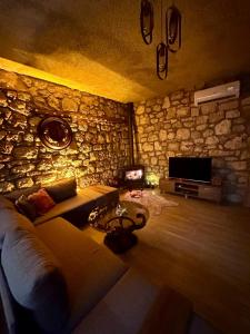 een woonkamer met een bank en een stenen muur bij Kösedere Stone Houses in Karaburun