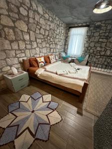 een slaapkamer met een groot bed en een stenen muur bij Kösedere Stone Houses in Karaburun
