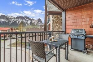 een tafel en stoelen op een balkon met een grill bij Rockies Getaway Condo With Mountain View in Canmore