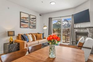 een woonkamer met een bank en een tafel met bloemen bij Rockies Getaway Condo With Mountain View in Canmore
