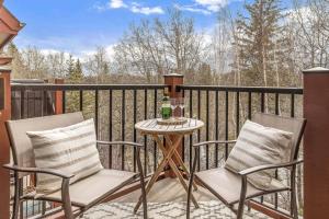 twee stoelen en een tafel op een balkon bij Rustic Creekside Retreat 2BR with Stunning View in Canmore