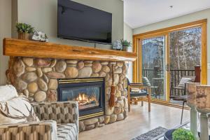 een woonkamer met een stenen open haard en een tv bij Rustic Creekside Retreat 2BR with Stunning View in Canmore