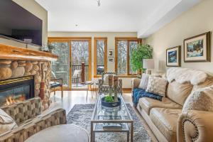 een woonkamer met een bank en een open haard bij Rustic Creekside Retreat 2BR with Stunning View in Canmore