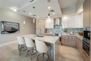 eine Küche mit weißen Schränken und eine Insel mit Barhockern in der Unterkunft Chic Three-Bedroom Waterfront Condo With Private Balcony in Fort Lauderdale