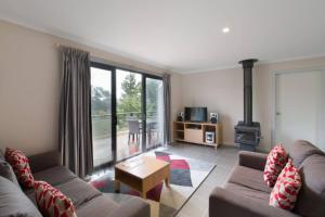 een woonkamer met een bank en een open haard bij Bush Rock Touchdown Cottages in Jindabyne