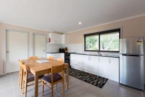 een keuken met een houten tafel en een koelkast bij Bush Rock Touchdown Cottages in Jindabyne +17 foto's