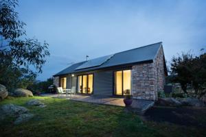 een klein stenen huis met een zwart dak bij Brumbies Run Touchdown Cottages in Jindabyne