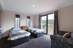 een slaapkamer met 2 bedden en een bank bij Brumbies Run Touchdown Cottages in Jindabyne
