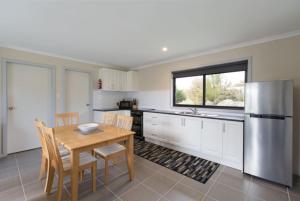 een keuken met een tafel en een roestvrijstalen koelkast bij Brumbies Run Touchdown Cottages in Jindabyne