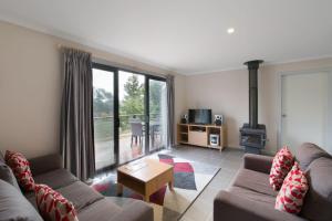 een woonkamer met een bank en een open haard bij Runway View Cottage at Touchdown Cottages in Jindabyne