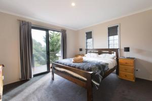 een slaapkamer met een bed en een groot raam bij Runway View Cottage at Touchdown Cottages in Jindabyne