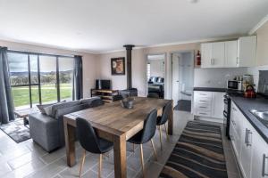 een keuken en woonkamer met een tafel en een bank bij Runway View Cottage at Touchdown Cottages in Jindabyne