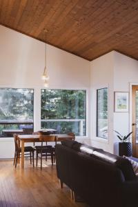 a living room with a table and a couch at Marielles Lookout - Your Oceanfront Escape Framed by Forest & Waves in Tofino